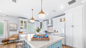 A modern kitchen with white cabinetry, a central island, and pendant lighting. - Beachfront Heated Pool & Hot Tub W Mini Putt (St. Augustine)