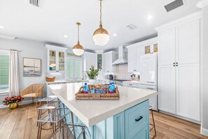 A modern kitchen with white cabinetry, a central island, and pendant lighting. - Beachfront Heated Pool & Hot Tub W Mini Putt (St. Augustine)