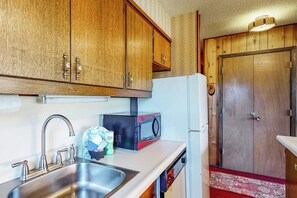 A kitchen with wooden cabinets, a stainless steel sink, a microwave, and a refrigerator. - Ski-in/ski-out Purgatory condo with balcony overlooking the gondola (Durango)