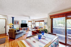 A spacious living room with a television, sofas, a coffee table, and a large window. - Comfortable condo with full kitchen, balcony, & washer/dryer (Durango)