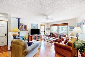 A living room with a television, sofas, a coffee table, and a ceiling fan. - Comfortable condo with full kitchen, balcony, & washer/dryer (Durango)