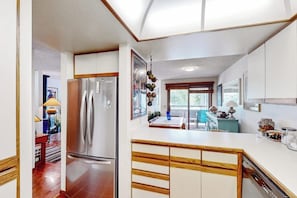 A modern kitchen with a stainless steel refrigerator, wooden cabinets, and a white countertop. - Comfortable condo with full kitchen, balcony, & washer/dryer (Durango)