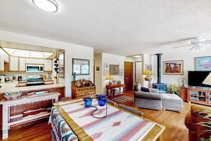 A spacious living area with a sofa, a television, and a kitchen area with cabinets and a microwave. - Comfortable condo with full kitchen, balcony, & washer/dryer (Durango)