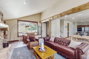 Ein geräumiges Wohnzimmer mit einer Ledersofa, einem Holztisch und einem Kamin aus Stein.