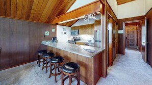 Eine Küche mit Holzausstattung, einer Marmorarbeitsplatte und einer Bar mit Hockern.