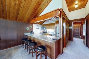 Eine Küche mit Holzausstattung, einer Marmorarbeitsplatte und einer Bar mit Hockern.