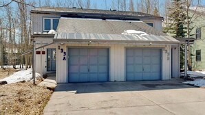 Une maison à deux étages avec un garage, une véranda et un petit abri attenant.