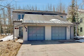 Ein zweistöckiges Haus mit Garage, einer Veranda und einem kleinen angebauten Geräteschuppen.