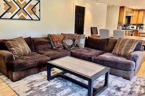 A sectional sofa with multiple cushions, a coffee table, and a patterned rug in a living room. - Upper apartment with deluxe kitchen, private W/D, & great location (Durango)