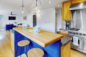 A modern kitchen with a central island, bar stools, a stainless steel stove, and wooden cabinets. - Upper apartment with deluxe kitchen, private W/D, & great location (Durango)