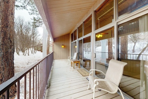 Eine überdachte Veranda mit Holzbalkon, einer Bank und einem Stuhl.