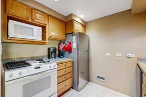 A kitchen with wooden cabinets, a stainless steel refrigerator, a microwave, an oven, and a coffee maker. - Cozy condo with private washer and dryer, on-site golf, share pool and hot tub (Durango)