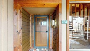 Eine Holztür mit Hausnummer und Fenster mit Blick auf eine Treppe.