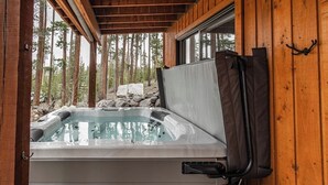 Ein Whirlpool in einer Holzhütte mit Blick auf einen Wald.