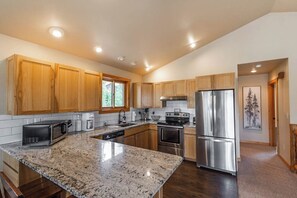 A modern kitchen with wooden cabinets, stainless steel appliances, and a granite countertop. - Riverfront Hot Tub Mountain Retreat (Grand Lake)