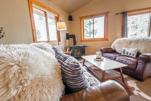 A cozy living room with a fireplace, leather sofas, and a large furry rug. - Riverfront Hot Tub Mountain Retreat (Grand Lake)