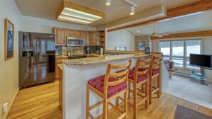 A modern kitchen with a central island, bar stools, stainless steel appliances, and a large window. - Spacious resort home w/private garage, hot tub & laundry. Bus to slope (Copper Mountain)
