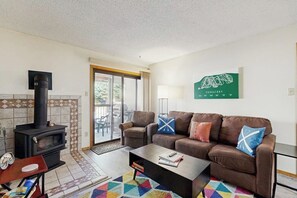 Ein Wohnzimmer mit Kamin, einer Couch, einem Couchtisch und einem bunten Teppich.