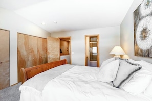 A bedroom with a bed, wooden wardrobe, and a painting on the wall.