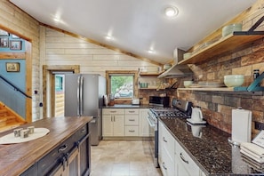 Eine moderne Küche mit Holzelementen, einem Edelstahlkühlschrank und einem eingebauten Herd.