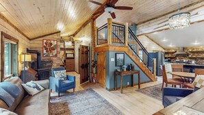 A spacious interior with a wooden ceiling, a staircase leading to an upper level, a cozy seating area with a sofa and chairs, and a kitchen area. - Mountain home with gas fireplace, dog-friendly and outdoor deck with BBQ (Durango)