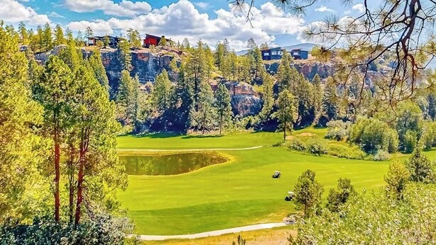 Golfkenttä, jossa on lampi, ja jota ympäröivät puut sekä kivinen kallio.
