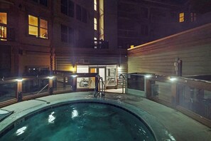 Ein Poolbereich im Innenbereich mit Glasveranda, einer Treppe zu einer erhöhten Ebene und einer Gebäudefassade mit Fenstern.
