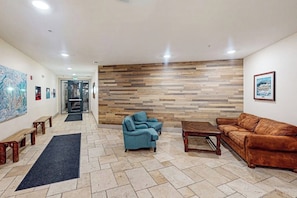 Eine Lobby mit einer Holzwand, einem blauen Sofa, einem braunen Sofa und einem Holztisch.