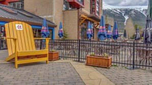 Een terras van bakstenen met buitenmeubilair, Red Bull paraplu's en een gele stoel.