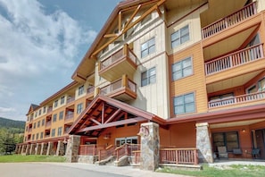 A multi-story hotel with balconies, a stone foundation, and a covered entrance. - Home w/shared fitness center, billiard table, hot tub walk to lifts (Copper Mountain)
