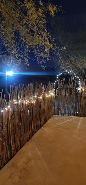 A nighttime outdoor area with a concrete path, decorative string lights, and a backdrop of trees and a building. - Casa de Ladrillo
House of Bryck An Experience
Mud adobe from 1920's  (Tucson)