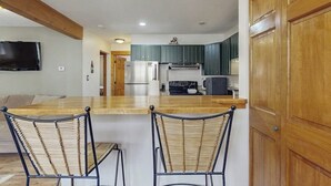 A kitchen with wooden cabinets, a built-in microwave, and a large island with two chairs. - Cozy home w/ wood fireplace, near town - mountain views (Frisco)