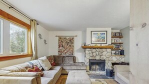 A cozy living room with a stone fireplace, a sofa, an ottoman, and a bookshelf. - Cozy home w/ wood fireplace, near town - mountain views (Frisco)