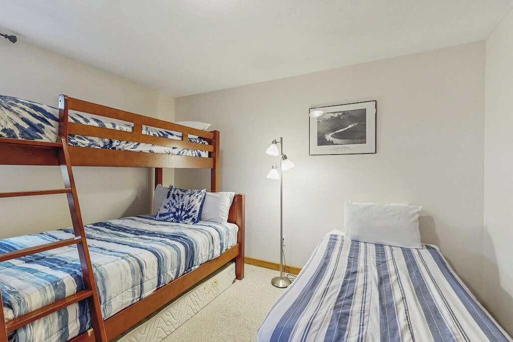 A room with bunk beds, a bedside lamp, and a framed picture on the wall.