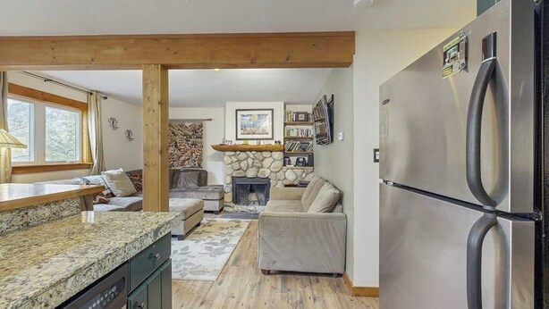 A kitchen with granite countertops, a built-in dishwasher, a large stainless steel refrigerator, and a stone fireplace. - Cozy home w/ wood fireplace, near town - mountain views (Frisco)