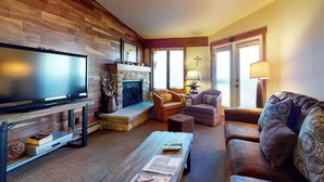 Una sala de estar con televisión, chimenea, sofás de cuero y una mesa de centro.