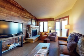 Ein Wohnzimmer mit Fernseher, Kamin, Ledersofas und einem Couchtisch.