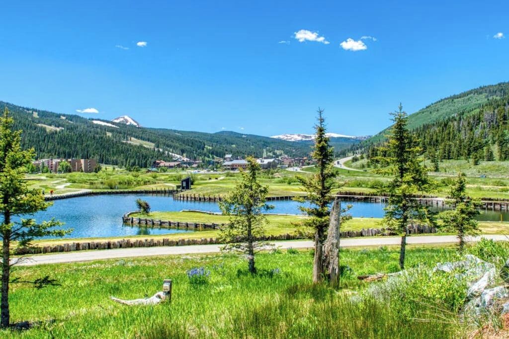 A lakeside view with a small building, trees, and a distant mountain.