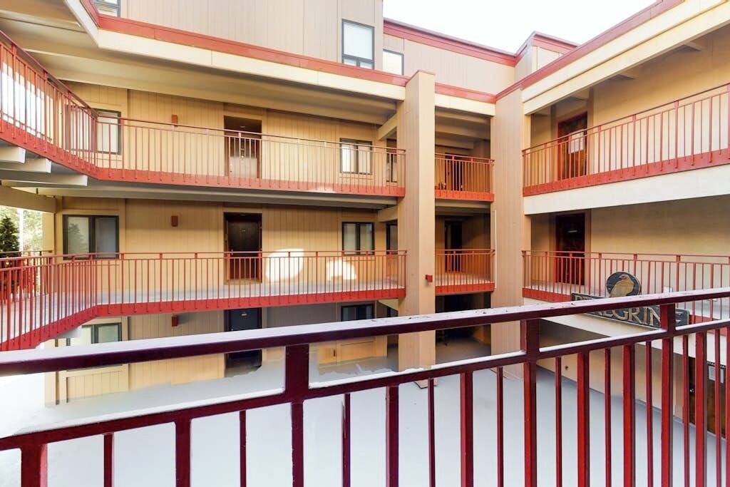 A multi-story building with balconies, a central stairwell, and a sign with a bird logo.