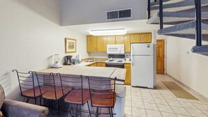 A compact kitchen with wooden cabinets, a white refrigerator, and a microwave.