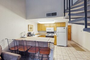 A compact kitchen with wooden cabinets, a white refrigerator, and a microwave.