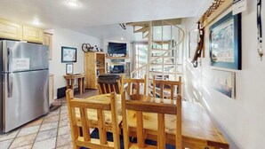 A kitchen with a built-in refrigerator, wooden dining table, chairs, and a spiral staircase. - Dog-friendly, ski condo with golf course views, balcony, hot tub & sauna (Copper Mountain)