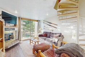 A modern living room with a fireplace, a sofa, a coffee table, and a staircase.