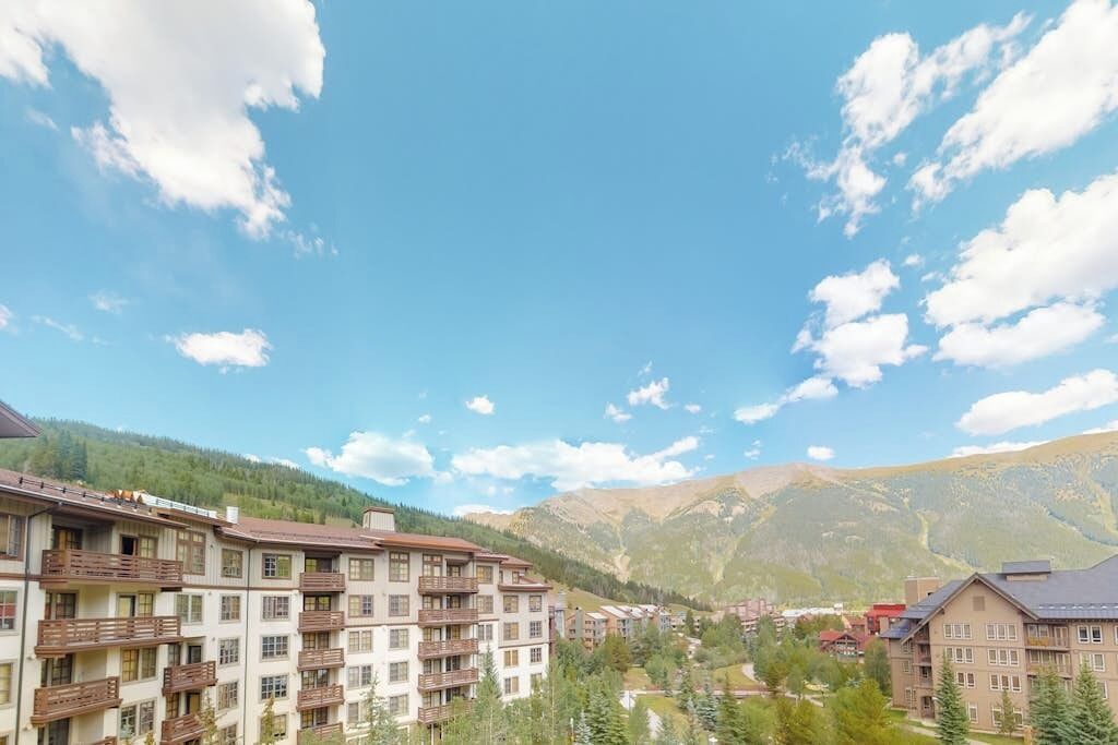 Un hôtel à plusieurs étages, doté de balcons, situé dans un cadre montagneux.