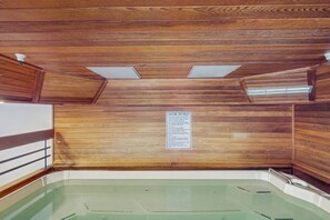 Ein Spa-Raum mit Holzwänden, einer in Glas eingefassten Whirlwanne und einem Warnschild.