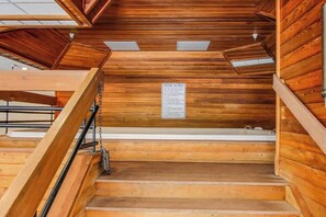 Eine Holztreppe mit einem Warnschild, einem Oberlicht und Blick auf die darüberliegende Etage.