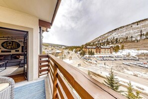 A balcony with a view of a parking lot, a building with multiple floors, and a snow-covered hillside. - Spacious & Bright Condo W/ Shared Pool, Easy Ski Access & Free WiFi (Copper Mountain)