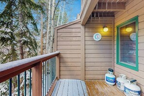 Eine Holzterrasse mit Gasflaschen, einer Uhr und einem Fenster mit grünem Rahmen.