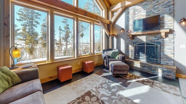 Una sala de estar acogedora con ventanas amplias, una chimenea de piedra y un espacio de descanso confortable.