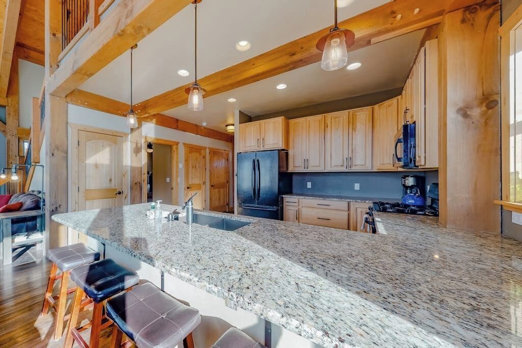 Una cocina amplia con encimeras de granito, armarios de madera y una isla grande con taburetes de bar.